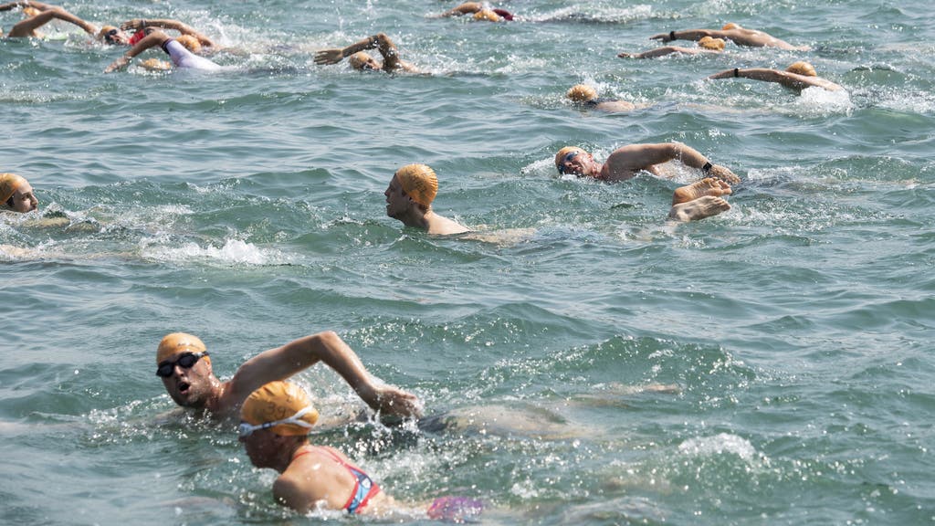 Teilnehmerinnen und Teilnehmer der Zürcher Seeüberquerung stürzen sich bei hochsommerlichen Temperaturen in das erfrischende Wasser des Zürichsees.