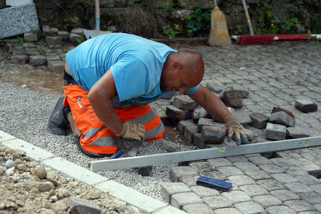Strassensanierung in Mühledorf: Arbeiter legt die Steine genau aneinander.