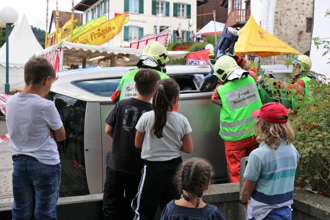 Interessiert verfolgt eine Schar Kinder aus nächster Nähe, wie die Feuerwehr eine Person aus einem umgekippten Auto rettet.