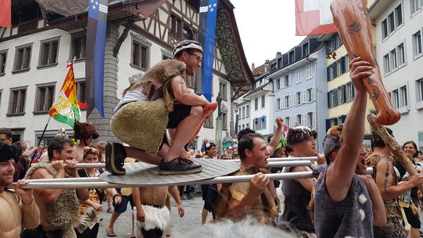 Die Höhlenmenschen sind los - mit Keule und Lendenschurz. Die “Urgauer Turner” aus Märwil TG verteilten Apfelsaft an die Zuschauer - auch an unsere Reporterin auf dem Balkon des Rathauses (Das Video dazu gibt es im Liveblog).