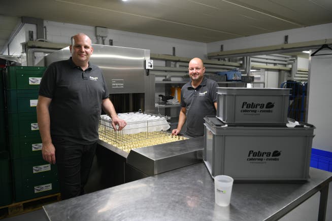 Markus Mehr und Peter Traub vor der neuen 10 Meter langen Abwaschmaschine speziell für Mehrweggeschirr aus Kunststoff.