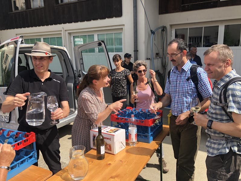 FDP-Grossrätin Martina Sigg und SVP-Generalsekretär Pascal Furer (links) empfangen die Wanderer und Wanderinnen in Schinznach-Dorf und schenken einheimischen Most und Wein aus.