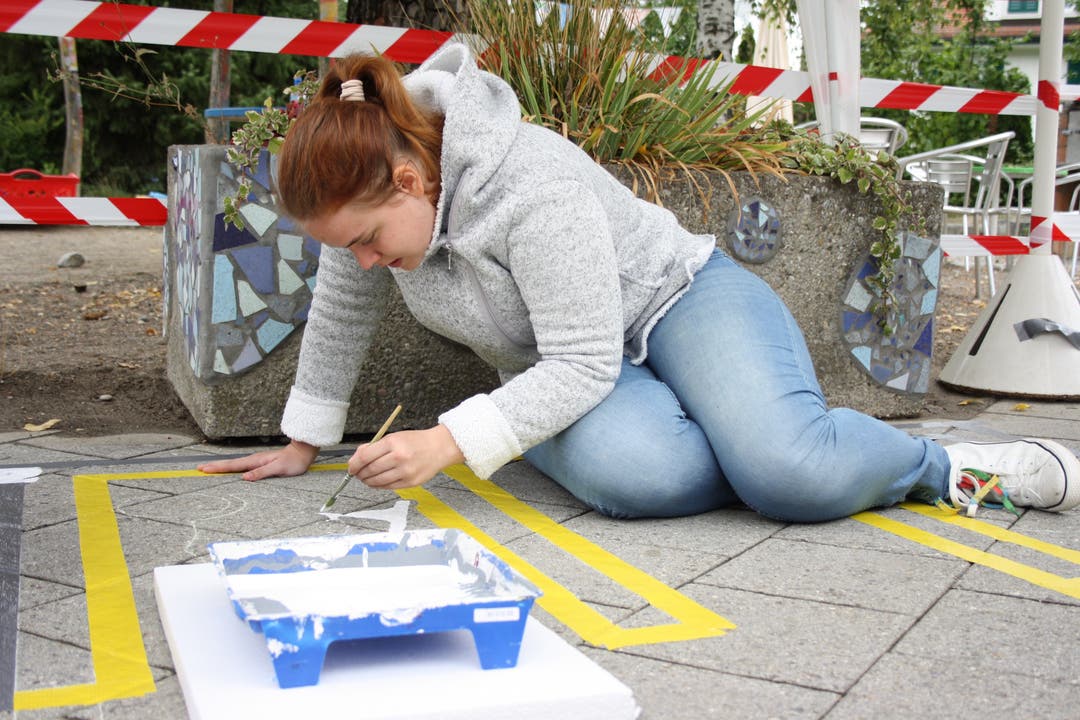  Mit Strassenmarkierungsfarbe malt Mirjam Bieler einen Parkplatz für Bobbycars und Spielzeugtraktoren auf den Boden.