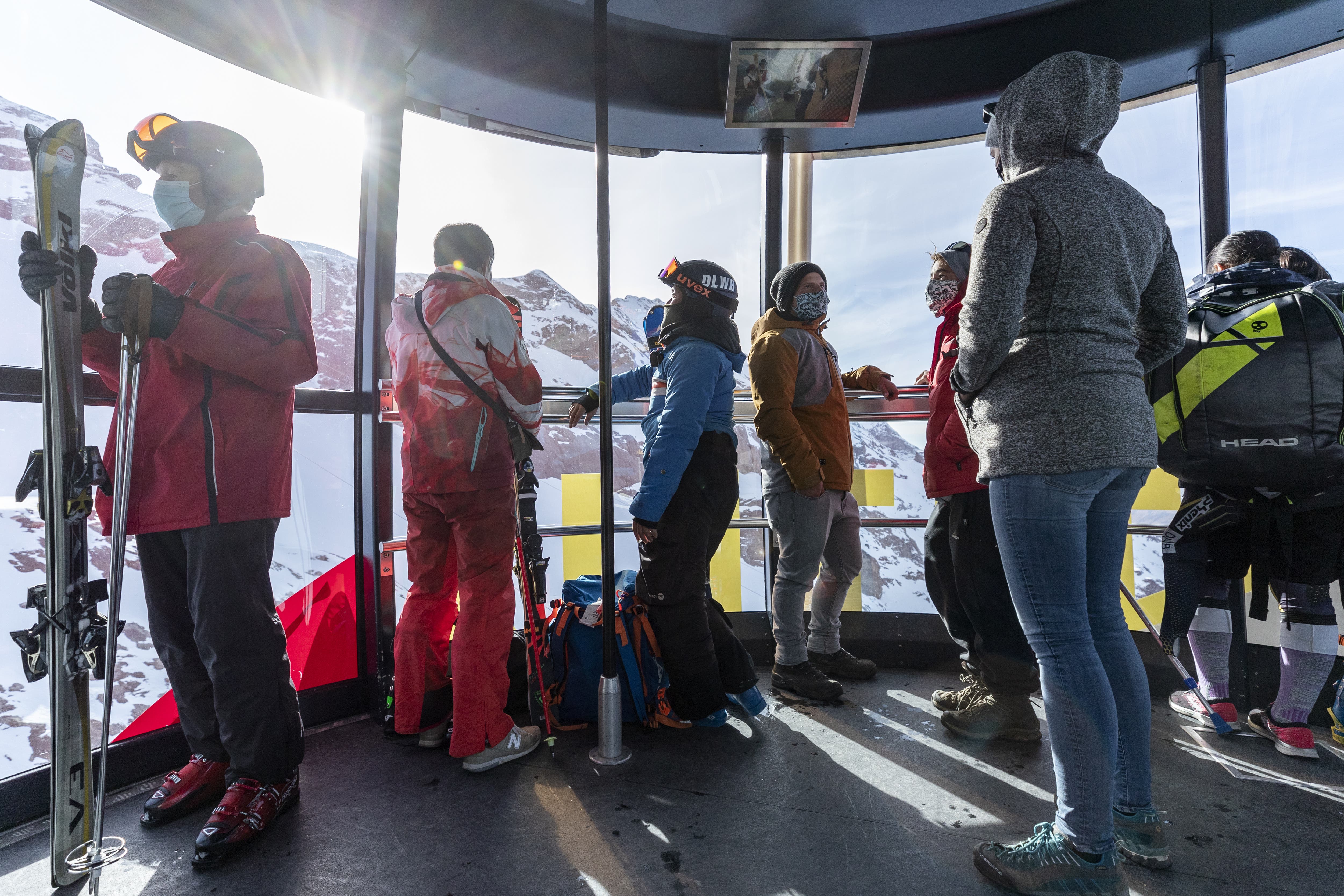Skifahrer mit Atemschutzmasken sind mit der Luftseilbahn Rotair auf den Titlis unterwegs