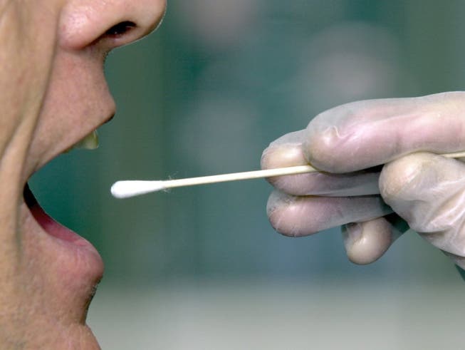 Einem Mann wird mit einem Wattestäbchen eine Speichelprobe zum DNA-Test entnommen.