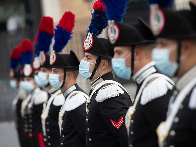 Eine Gruppe italienischer Carabinieri trägt während der Feierlichkeiten zum Tag der Streitkräfte Mund-Nasen-Schutz. Foto: Alessandra Tarantino/AP/dpa