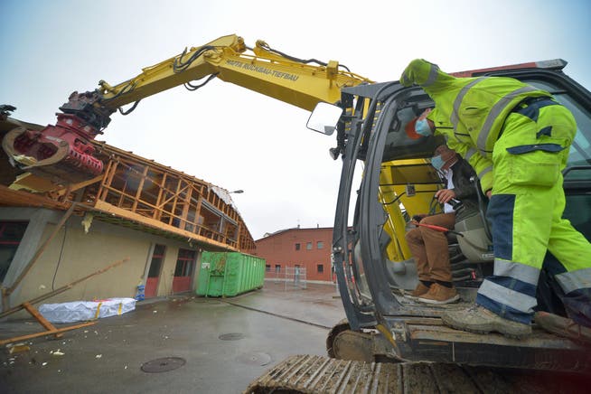 Gemeindepräsident Kilian Germann reisst mit dem Bagger ein erstes Stück der Dachkonstruktion des alten Werkhofs runter.