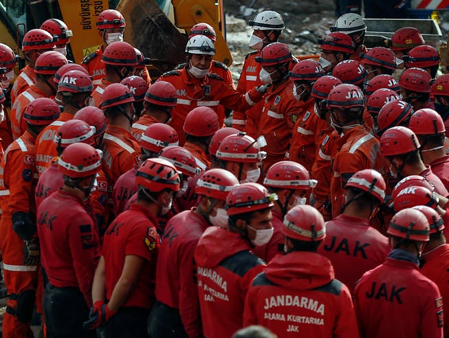 Mitglieder von Rettungsdiensten stehen für eine Lagebesprechung zusammen. Fünf Tage nach dem verheerenden Erdbeben im türkischen Izmir haben Einsatzkräfte die Rettungsarbeiten beendet. Foto: Emrah Gurel/AP/dpa