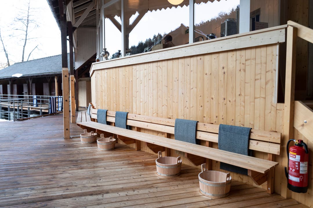 Bereit für die Saunagäste: Die Sitzbanke vor dem Saunabistro mit Holzbottichen und Tüchern.