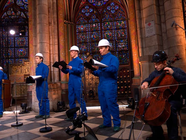 HANDOUT - Cellist Gautier Capucon (r) und der Chor der Kathedrale Notre Dame zeichnen ein Weihnachtskonzert auf. Foto: Musique Sacree à Notre-Dame de Paris/MSNDP/AP/dpa