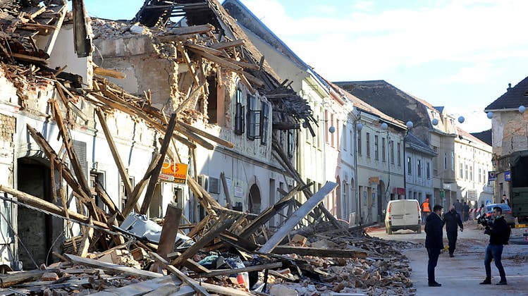 Zwei Passanten machen ein Foto vor den Trümmern eines durch ein Erdbeben eingestürzten Hauses. (Keystone/AP)