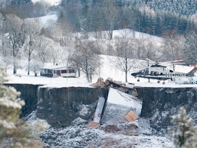 dpatopbilder - Ein Helikopter fliegt über die Stelle, an der ein Erdrutsch zahlreiche Häuser in die Tiefe gerissen oder zerstört hat. Foto: Fredrik Hagen/NTB/dpa