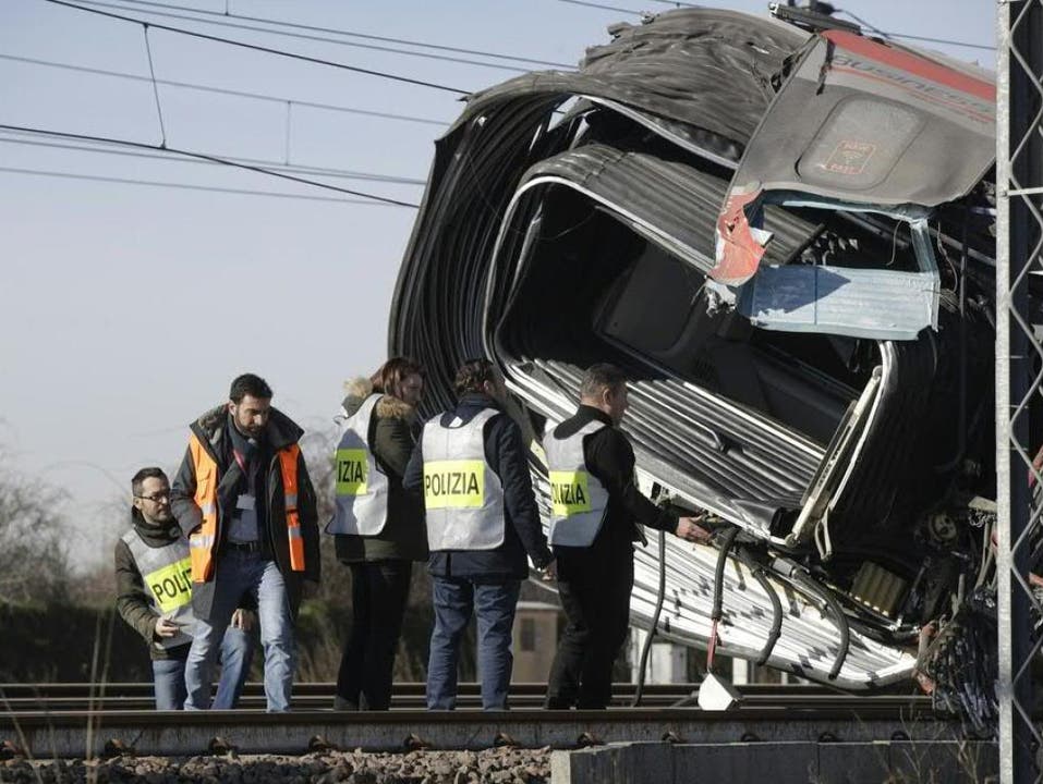 Spezialisten der Polizei untersuchen den verunglückten Zug in Norditalien.