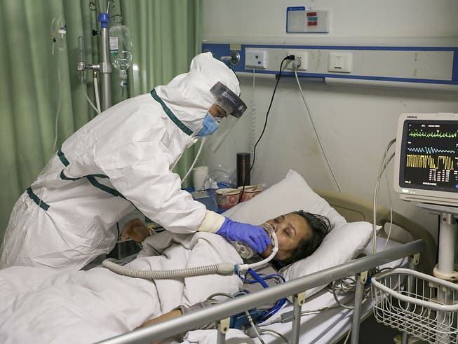 Eine Pflegefachfrau in einem Spital in der chinesischen Stadt Wuhan gibt einem am neuartigen Coronavirus erkrankten Patienten Wasser ein.