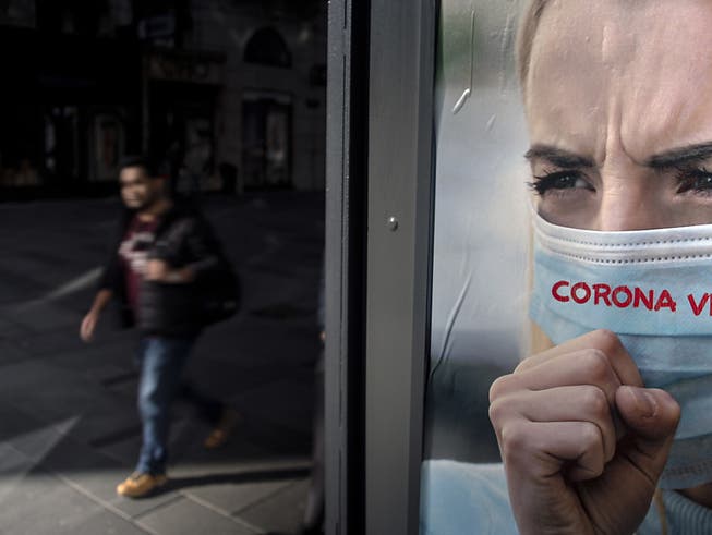 Ein Mann spaziert an einem Werbeplakat gegen das Coronavirus in Wien vorbei.