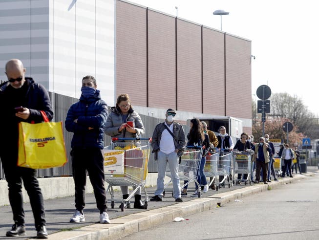 Kundinnen und Kunden warten vor einem Supermarkt in Italien auf Einlass.