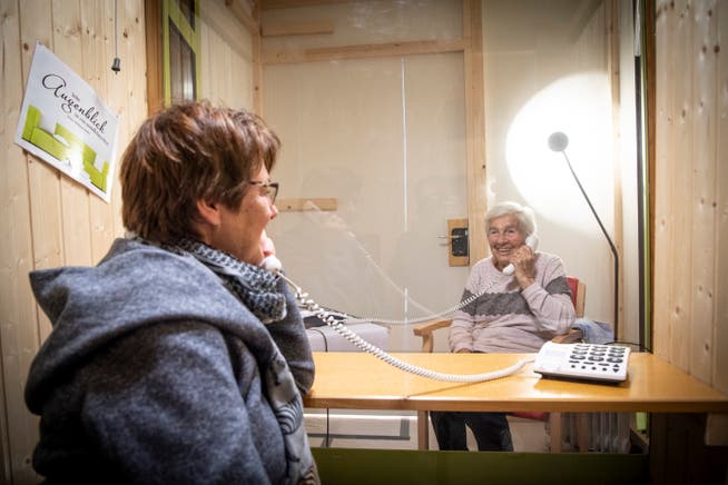 Getrennt durch eine Scheibe, verbunden per Telefon: Trudi Jäger unterhält sich mit ihrer Mutter Hilda Schläpfer in der Besuchsbox des Alters- und Pflegeheims Risi. 