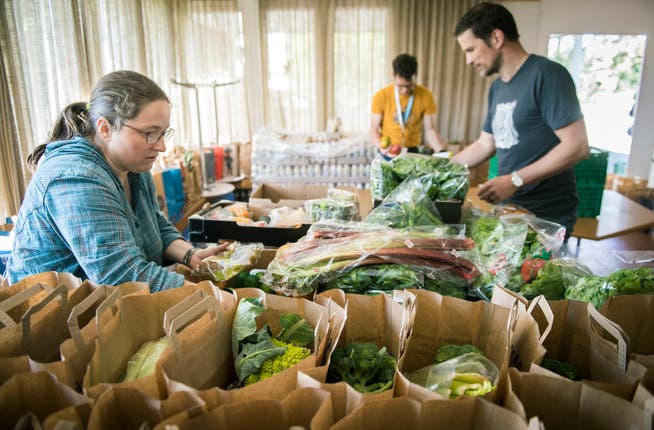 Helfer der Verwertbar packen in Kreuzlingen Lebensmittel in Papiersäcke, um sie Bedürftigen abzugeben.