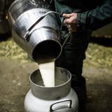 Ein Bauer leert Milch von einer Kanne in eine andere um. (Bild: Luca Linder)