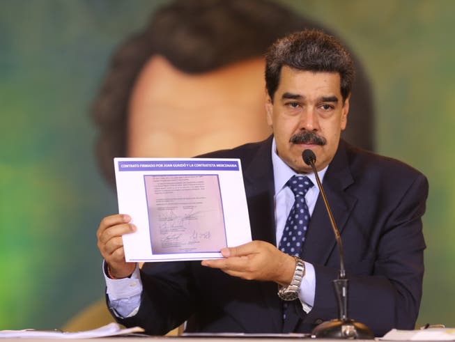HANDOUT - Auf diesem vom venezolanischen Präsidentenamt zur Verfügung gestellten Bild zeigt Nicolas Maduro, Präsident von Venezuela, die Kopie eines Dokumentes, das beweisen soll, dass der Oppositionsführer Guaido einen angeblichen Invasionsversuch mit «terroristischen Söldnern» unterstützt haben soll. Die Regierung von Maduro versichert, «Söldner» hätten das Land angegriffen. Hinter dem Plan steckten Kolumbien und die USA. Das Präsidentenamt veröffentlichte ein Video, in dem ein festgenommener US-Bürger Details seiner Mitarbeit schildert. Foto: Marcelo Garcia/Prensa Miraflores/dpa - ACHTUNG: Nur zur redaktionellen Verwendung im Zusammenhang mit der aktuellen Berichterstattung und nur mit vollständiger Nennung des vorstehenden Credits