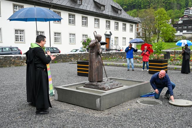 Abt Christian Meyer (links) segnet den Brunnen und die Skulptur zu Ehren von Abt Adelhelm, während Holzbildhauer Mario Fuchs die Wasserzufuhr zum Brunnen in Gang setzt. 