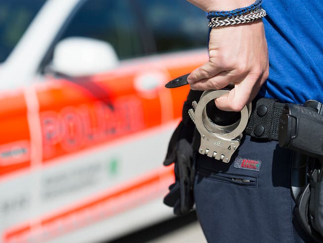 Ein Beamter der Kantonspolizei St. Gallen greift zu Handschellen.