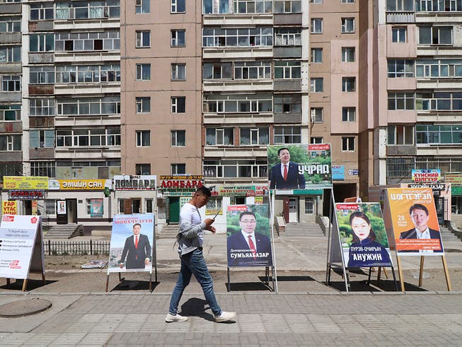 Ein Mann geht an Wahlplakaten verschiedener Parteien vorbei. Foto: Ganbat Namjilsangarav/AP/dpa