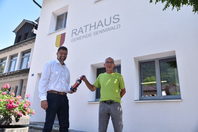 Amtsübergabe des Gemeindepräsidiums von Peter Kindler (rechts) an seinen Nachfolger Bertrand Hug mit einer Flasche Wein aus der Gemeinde.