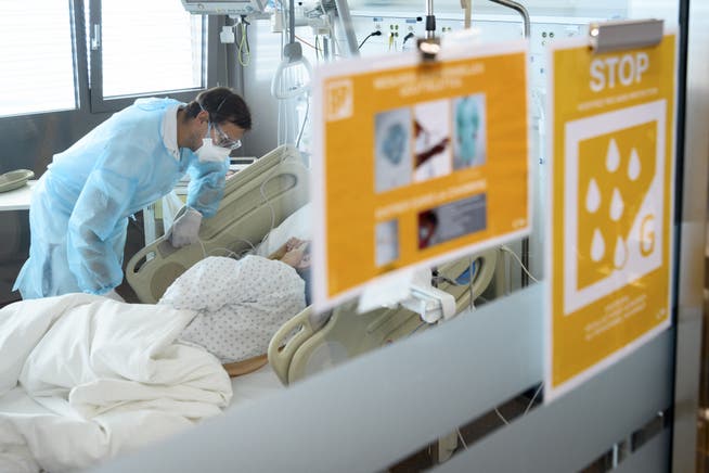 Ein Mitarbeiter betreut im Universitätsspital Lausanne einen am Coronavirus erkrankten Patienten. (Symbolbild)