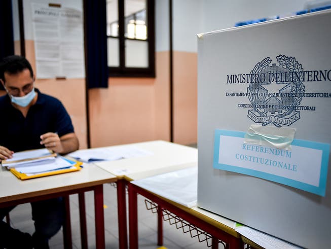 Ein Wahlhelfer sitzt an einem Tisch neben in der Parini-Mittelschule neben einer Wahlurne. Foto: Claudio Furlan/LaPresse via ZUMA Press/dpa