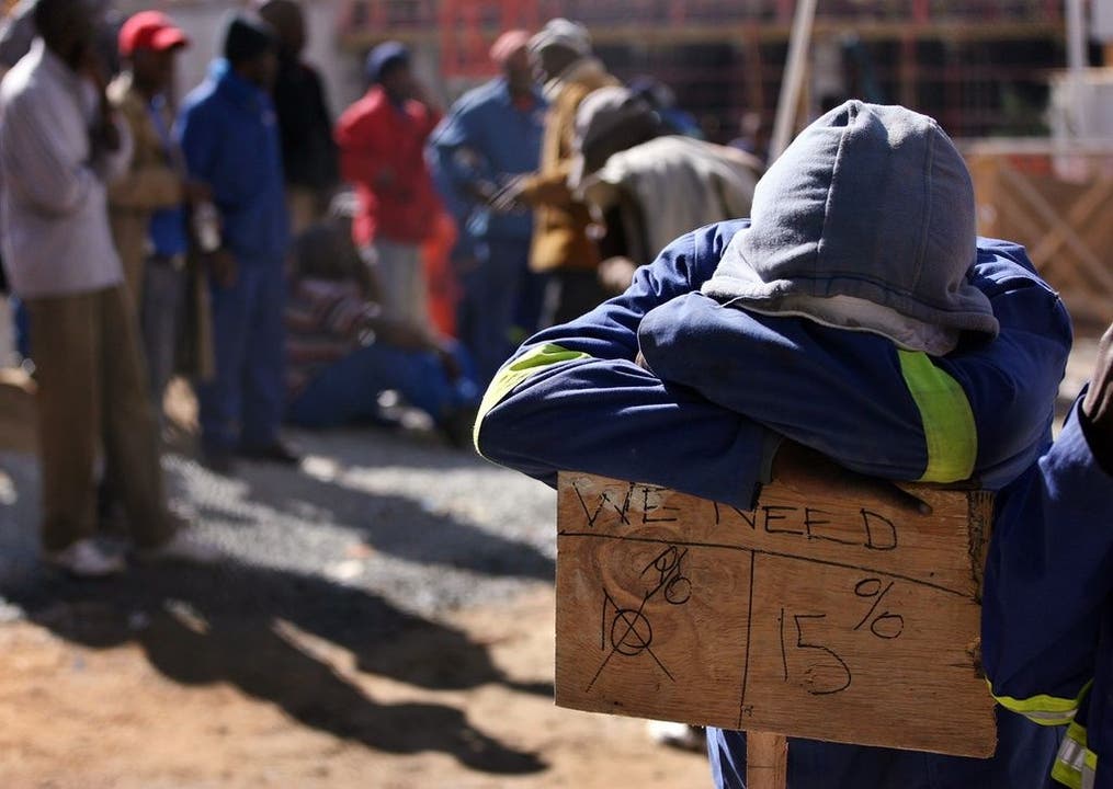Arbeiterstreiks in Südafrika Ein Arbeiter stützt sich auf ein Schild am Rande der Streiks.