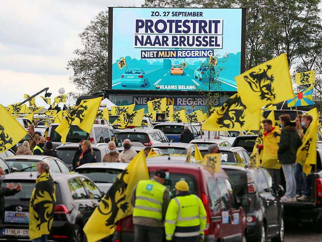 Demonstranten halten zwischen ihren Autos flämische Flaggen während des Protestes der rechtspopulistischen Regionalpartei Vlaams Belang gegen die Regierung. Foto: Nicolas Maeterlinck/BELGA/dpa