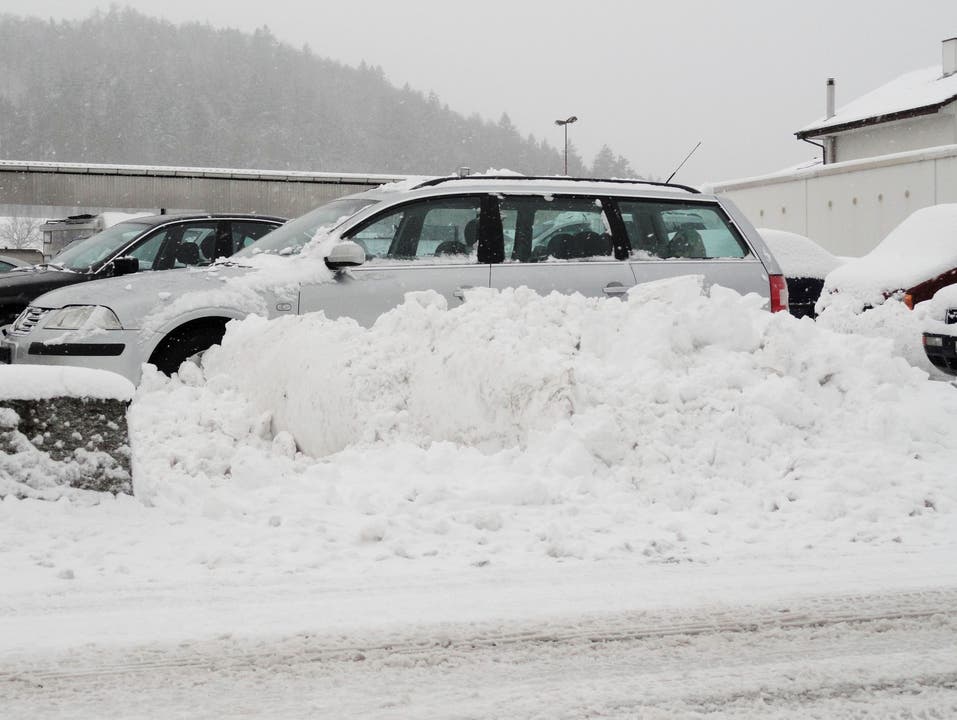  Hinter einer Schneemauer abgestellte Autos auf einem Parkplatz in Hunzenschwil Foto Walter Christen
