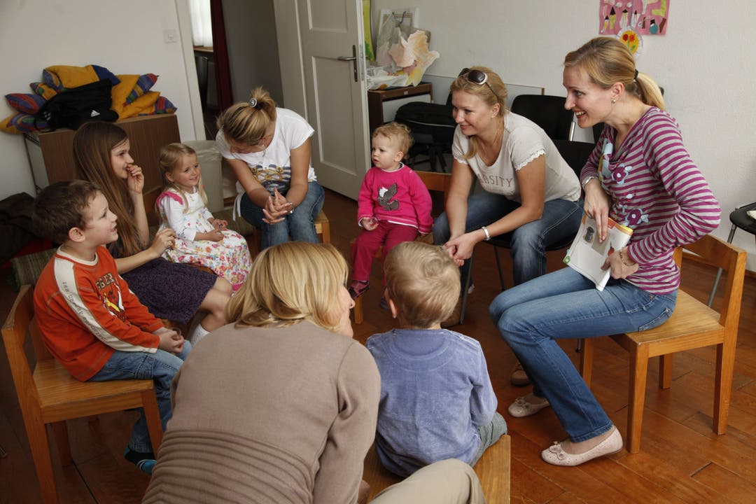 Sechs Kinder zwischen zwei und acht Jahren lauschen aufmerksam Geschichten und Märchen - auf Russisch