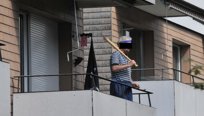R.W. mit einem Baseballschläger auf seinem Balkon.