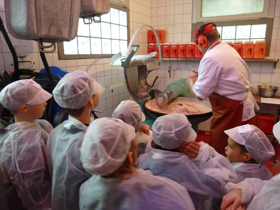 Die Kinderschar beobachtet gespannt, was Produktionsleiter Eugen Vogt mit der Fleischmasse macht