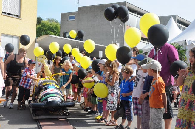 Die Kinder stehen mit schwarzen und gelben Ballonen, den Farben des Ennetbadener Wappens, für die Schlüsselübergabe Spalier. lbe