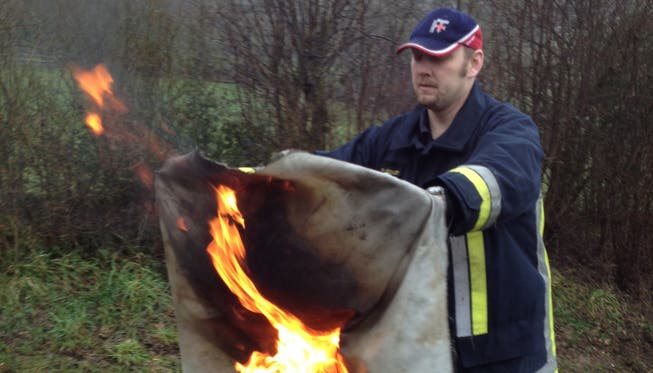 Feuerwehrkommandant Patrik Gfeller demonstriert, wie man einen brennenden Gegenstand mit der Branddecke löscht.