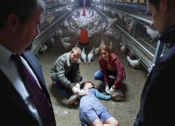 Die junge Hühnerbäuerin liegt tot im Stall, die Ermittlern fühlen ihr den Puls.
