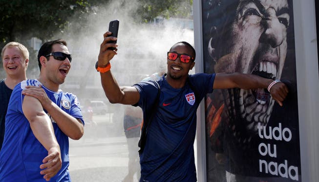 Fussballfans erlauben sich in Rio de Janeiro einen Spass vor einem Plakat von Luis Suarez.