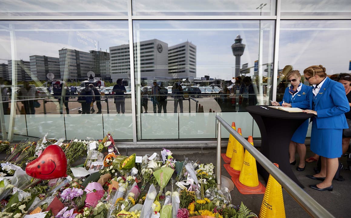 Eine Stewardess trägt sich am Amsterdamer Flughafen Schiphol ins Kondolenzbuch ein. Währendem versammeln sich Angehörige und wollen zur Absturzstelle fliegen.