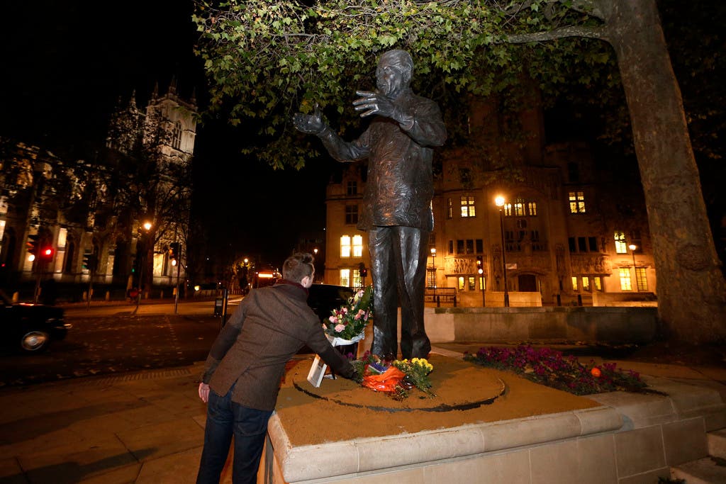 Ein Mann legt Blumen unter die Mandela-Statue im Parliament Square in London.