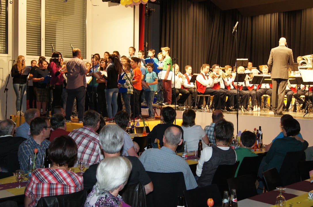 Der Jugendchor Künten (auf der Nebenbühne links) im Zusammenspiel mit der Brass-Band