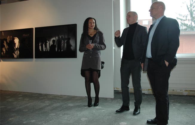 Stadtrat André Odermatt (rechts), Veranstalter Romano und Carmen Zerbini bei der Eröffnung der Photobastei vor Bildern von Paolo Pellegrini.