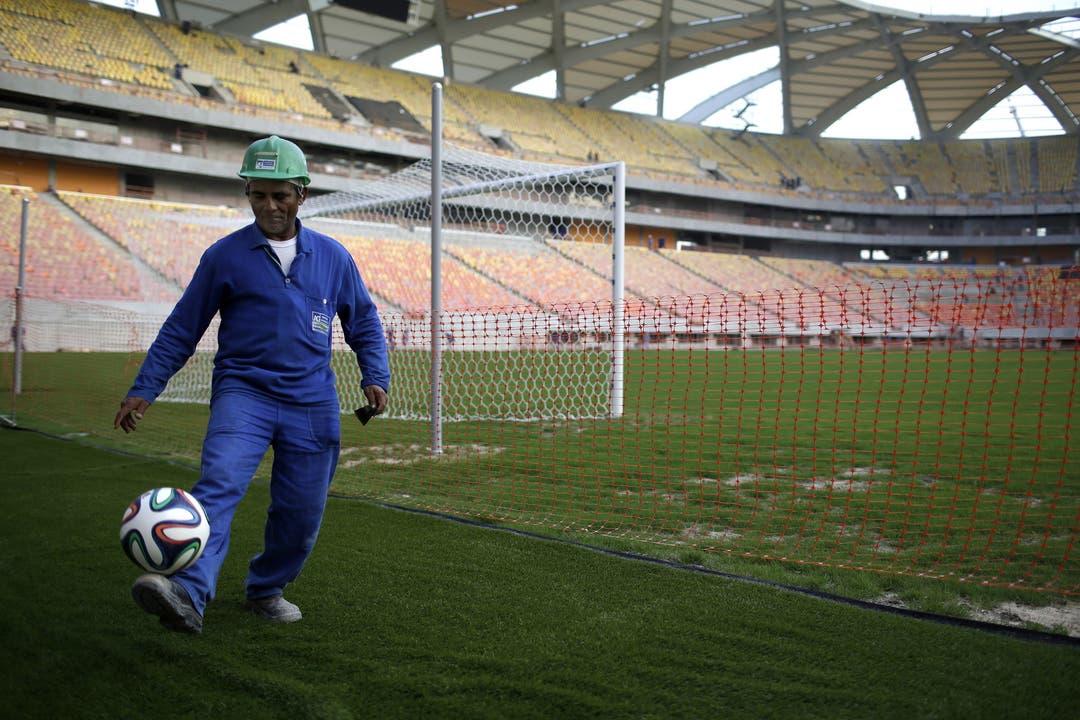 Erholsame Minuten für einen Bauarbeiter mit einem WM-Fussball am Rande der Bauarbeiten im Stadion von Manaus