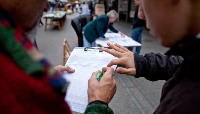 Passanten unterschreiben eine Volksinitiative. (Symbolbild)