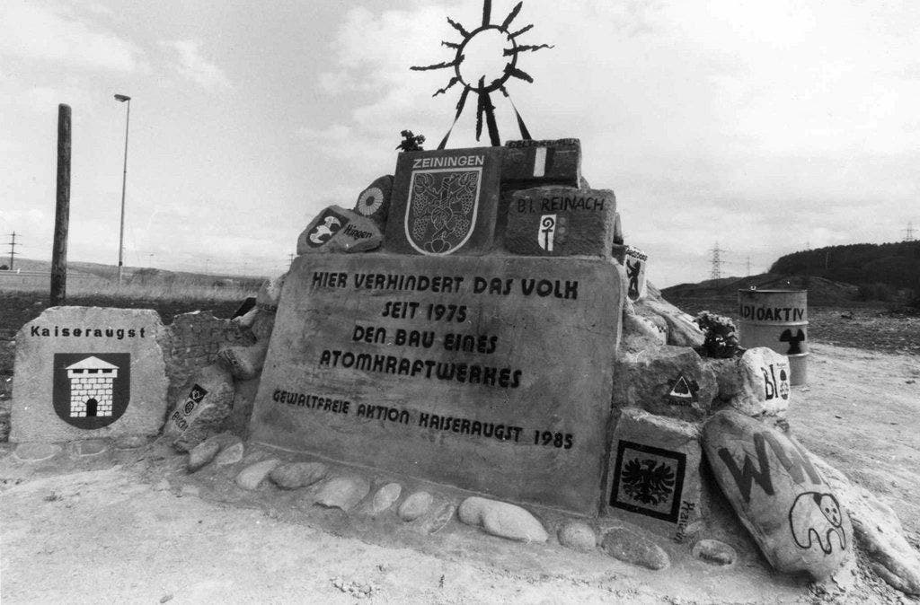 Protest-Denkmal in Kaiseraugst, aufgenommen 1985. In den Siebzigerjahren verstärkte sich im Zuge der Umweltdiskussion der Widerstand gegen die Kernenergie. Am 1. April 1975 besetzten Gegner das Baugelände für das geplante AKW Kaiseraugst. 1988 verzichtete man auf den Bau der geplanten AKW Kaiseraugst.