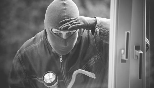 Einbrecher schaut durch ein Fenster. (Symbolbild)