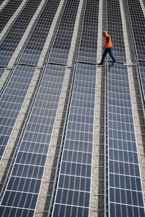 Ein Arbeiter geht über die Solarpanels.