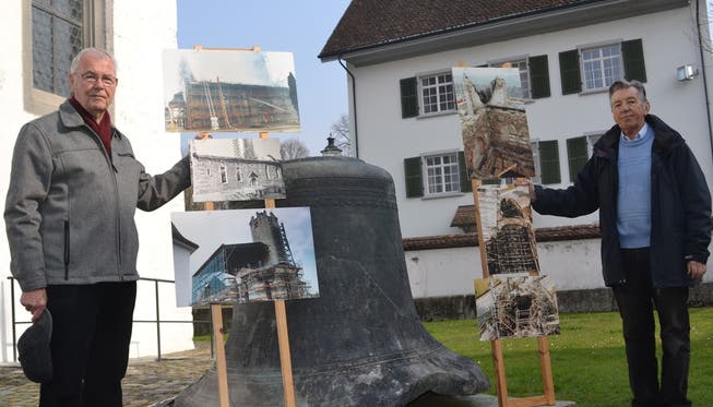 Hugo Huwyler (links) und Heinz Koch mit Teilen der Fotoausstellung zum Kirchenbrand, die morgen Samstag besichtigt werden kann; die Glocke in der Bildmitte ist das einzige Überbleibsel des einstigen beim Brand zerstörten achtstimmigen Glockengeläuts.sl
